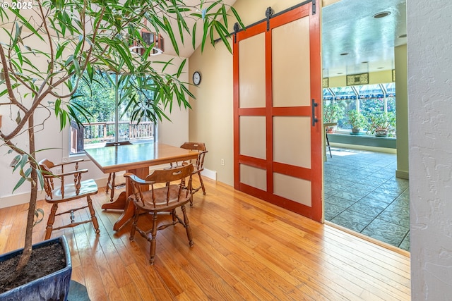 dining space featuring baseboards, a barn door, and light wood-type flooring