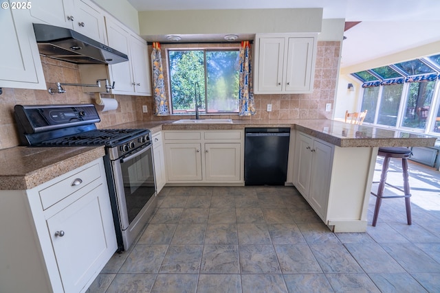 kitchen with gas stove, under cabinet range hood, black dishwasher, a sink, and tile countertops