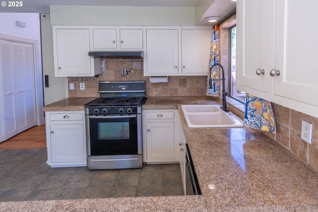 kitchen featuring range with gas stovetop, a sink, tile counters, backsplash, and white cabinetry
