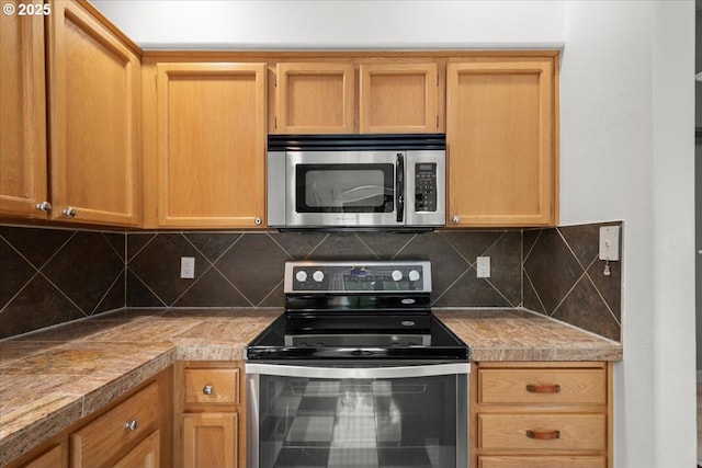 kitchen with stainless steel appliances, tile counters, and backsplash