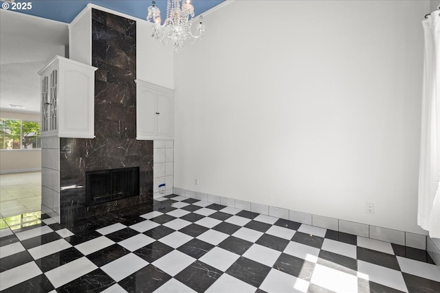 unfurnished living room with a fireplace, a chandelier, and a high ceiling