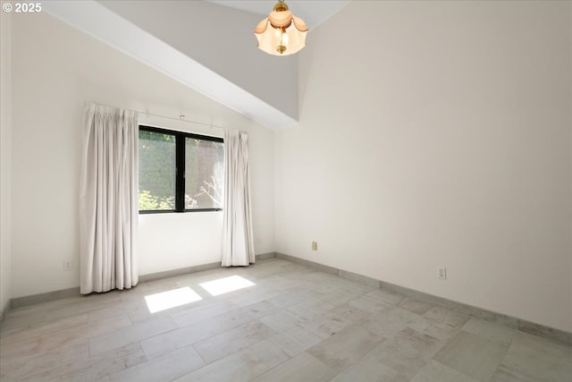 empty room featuring baseboards and high vaulted ceiling