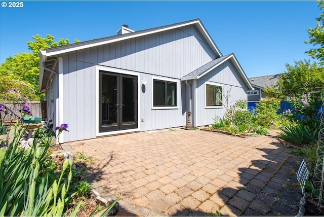 rear view of property with a patio, a chimney, french doors, and fence
