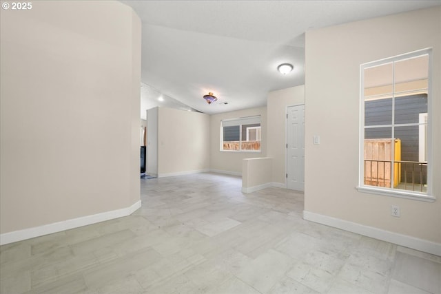 empty room with lofted ceiling and baseboards