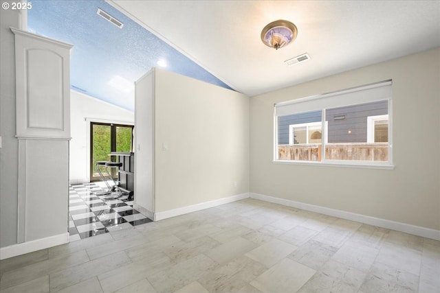 empty room featuring vaulted ceiling and baseboards