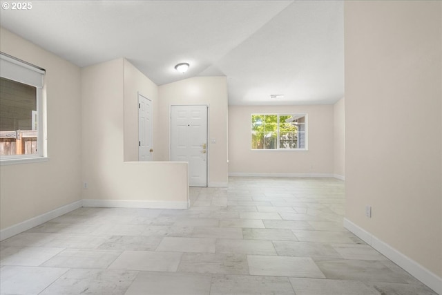 spare room featuring lofted ceiling and baseboards
