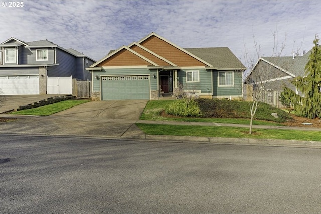 craftsman-style house featuring stone siding, fence, driveway, and an attached garage