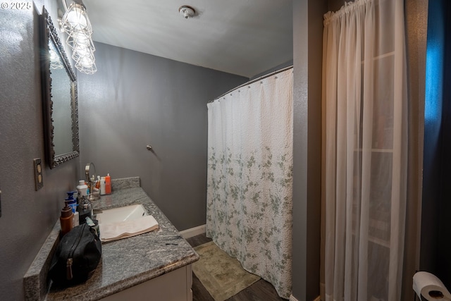 bathroom with a shower with curtain, baseboards, wood finished floors, and vanity