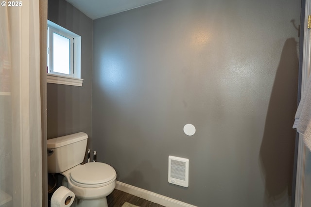 bathroom featuring toilet, baseboards, visible vents, and wood finished floors