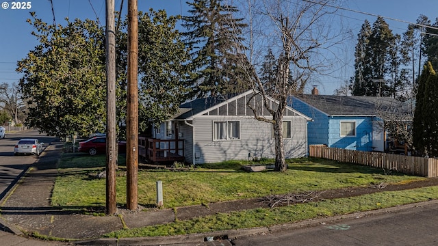 view of front of property featuring a chimney, roof with shingles, a front yard, and fence