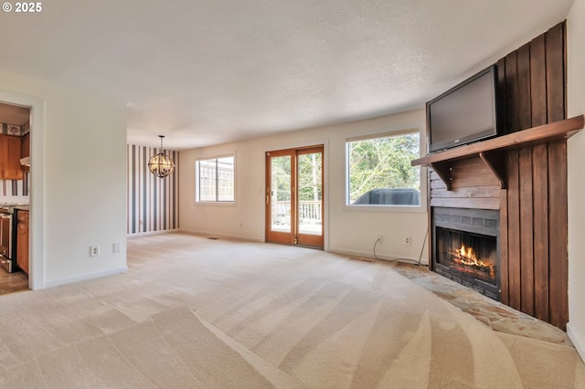 18005 SW Monte Verdi Blvd, Beaverton, OR 97007 - unfurnished living room featuring a fireplace, healthy amount of natural light, a chandelier, and light colored carpet
