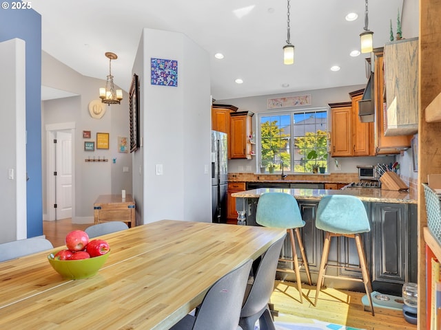 104 S Pl, Astoria, OR 97103 - kitchen with refrigerator with ice dispenser, a peninsula, a chandelier, a breakfast bar, and decorative light fixtures