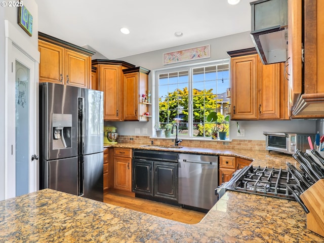 104 S Pl, Astoria, OR 97103 - kitchen featuring appliances with stainless steel finishes, light wood-style floors, brown cabinetry, light stone counters, and recessed lighting