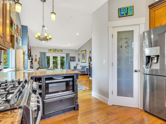 104 S Pl, Astoria, OR 97103 - kitchen featuring appliances with stainless steel finishes, a chandelier, brown cabinetry, vaulted ceiling, and light wood-style flooring