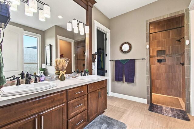 16215 NE 171st Ct, Brush Prairie, WA 98606 - bathroom featuring double vanity, walk in shower, baseboards, a walk in closet, and tile patterned floors