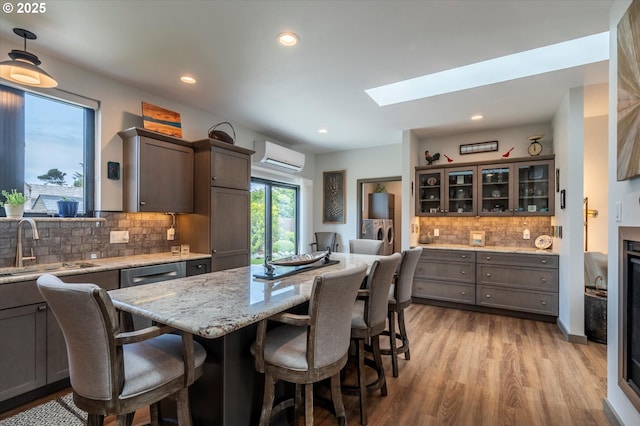 1342 11th St SW, Bandon, OR 97411 - kitchen featuring a wall unit AC, light wood finished floors, a kitchen breakfast bar, a skylight, and recessed lighting