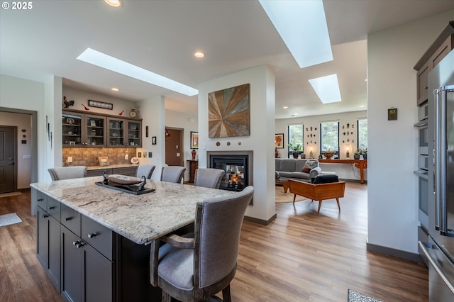 1342 11th St SW, Bandon, OR 97411 - kitchen with a skylight, wood finished floors, a kitchen breakfast bar, a multi sided fireplace, and recessed lighting