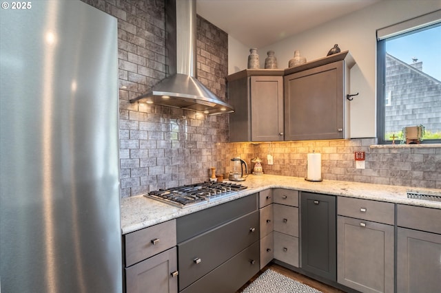 1342 11th St SW, Bandon, OR 97411 - kitchen with stainless steel appliances, wall chimney exhaust hood, gray cabinetry, backsplash, and light stone counters