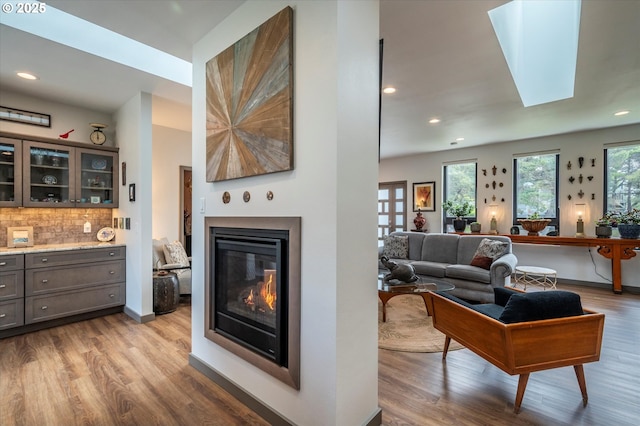 1342 11th St SW, Bandon, OR 97411 - living room featuring wood finished floors, a glass covered fireplace, recessed lighting, and a skylight