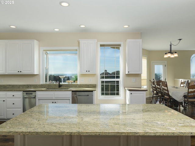 54179 Gould Rd, Bandon, OR 97411 - kitchen with a sink, stainless steel dishwasher, a center island, white cabinetry, and light stone counters