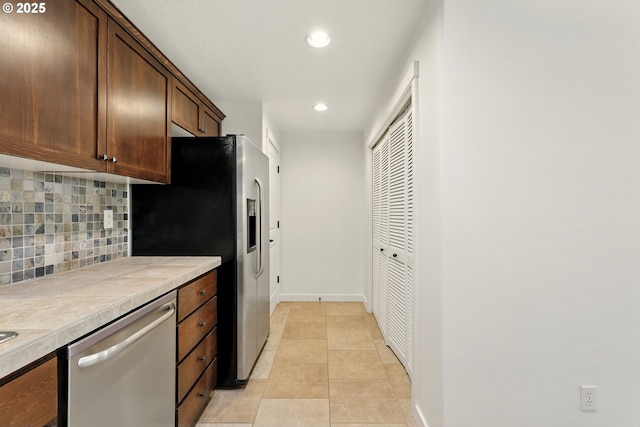 672 NE Newstead Ln, Hillsboro, OR 97006 - kitchen with dishwashing machine, tile countertops, backsplash, baseboards, and stainless steel fridge with ice dispenser