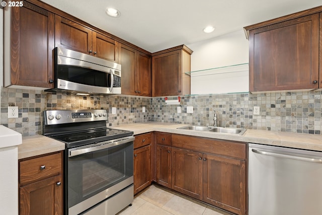 672 NE Newstead Ln, Hillsboro, OR 97006 - kitchen featuring stainless steel appliances, a sink, light countertops, light tile patterned floors, and backsplash