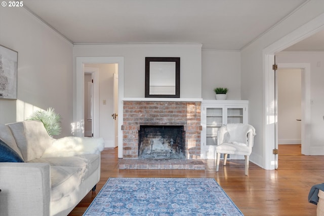 living room with a fireplace, wood-type flooring, and ornamental molding