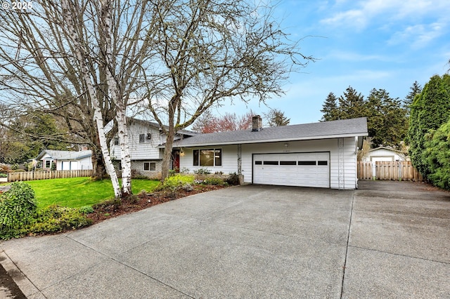 split level home with fence, driveway, a front yard, a garage, and a chimney