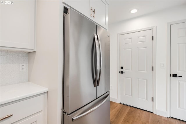 7143 SW Sagert St Unit 106, Tualatin, OR 97062 - kitchen featuring freestanding refrigerator, light wood finished floors, white cabinetry, backsplash, and light countertops
