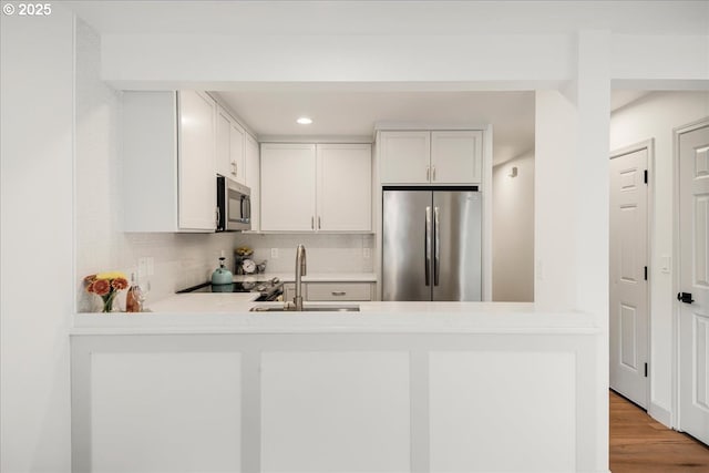 7143 SW Sagert St Unit 106, Tualatin, OR 97062 - kitchen with appliances with stainless steel finishes, a sink, tasteful backsplash, recessed lighting, and a peninsula