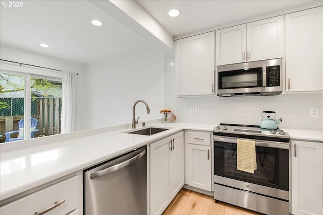 7143 SW Sagert St Unit 106, Tualatin, OR 97062 - kitchen with stainless steel appliances, a sink, white cabinetry, light countertops, and tasteful backsplash