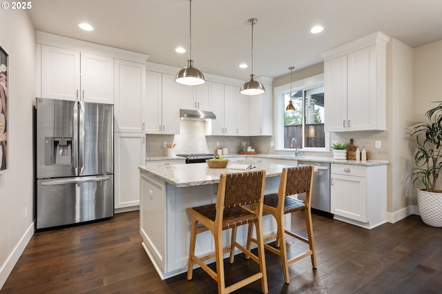 kitchen with white cabinetry, decorative light fixtures, stainless steel appliances, and a center island