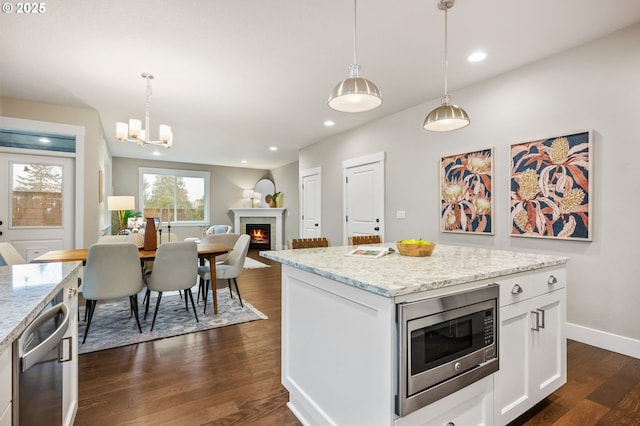 kitchen with decorative light fixtures, dark wood-type flooring, stainless steel appliances, and white cabinets