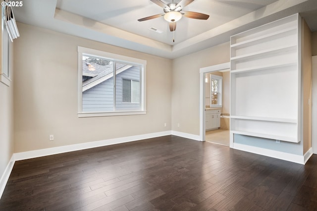 unfurnished bedroom featuring connected bathroom, dark hardwood / wood-style floors, a raised ceiling, and ceiling fan