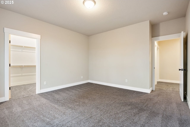 unfurnished bedroom featuring a walk in closet, carpet floors, a closet, and a textured ceiling