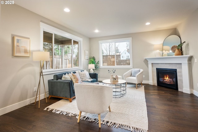 living room with a tile fireplace, a healthy amount of sunlight, and dark wood-type flooring