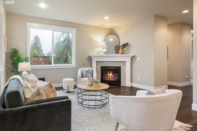 living room featuring a tiled fireplace and dark hardwood / wood-style flooring