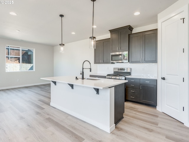 736 NW 178th Way, Ridgefield, WA 98642 - kitchen with appliances with stainless steel finishes, a kitchen island with sink, light countertops, light wood-style flooring, and recessed lighting