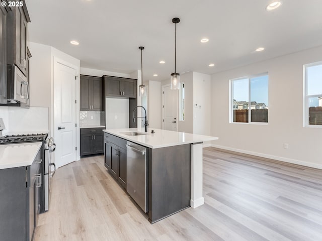 736 NW 178th Way, Ridgefield, WA 98642 - kitchen with appliances with stainless steel finishes, light wood-style flooring, tasteful backsplash, a kitchen island with sink, and light countertops