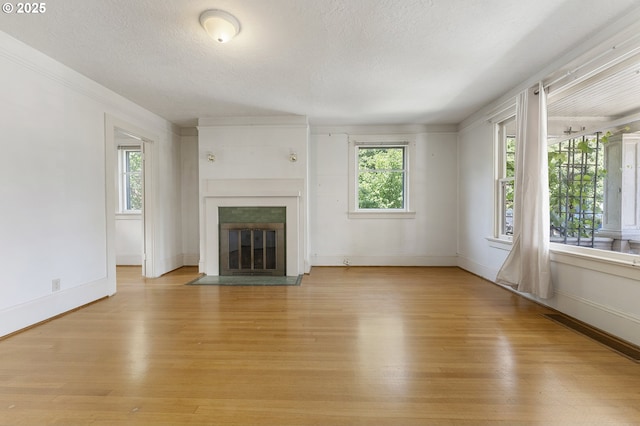 1904 SE Alder St, Portland, OR 97214 - unfurnished living room featuring light wood-style floors, plenty of natural light, a fireplace with flush hearth, and a textured ceiling