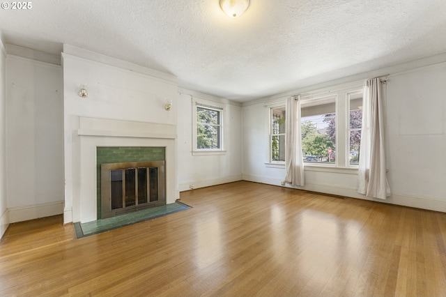 1904 SE Alder St, Portland, OR 97214 - unfurnished living room with wood finished floors, a tiled fireplace, baseboards, and a textured ceiling