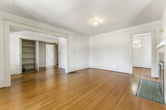 1904 SE Alder St, Portland, OR 97214 - unfurnished living room with light wood finished floors, baseboards, a textured ceiling, a fireplace, and crown molding