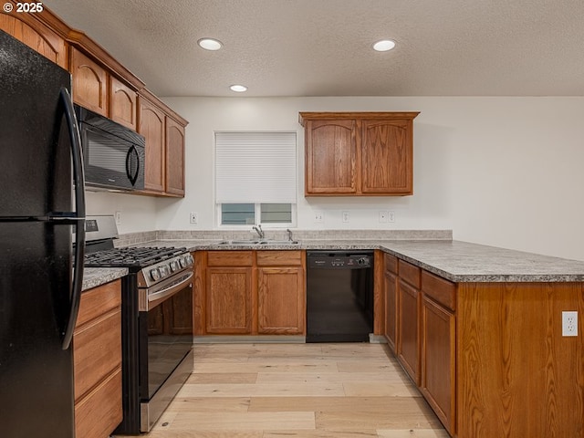 kitchen featuring sink, a textured ceiling, light wood-type flooring, kitchen peninsula, and black appliances