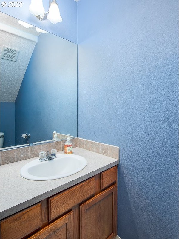 bathroom featuring vanity, an inviting chandelier, and toilet