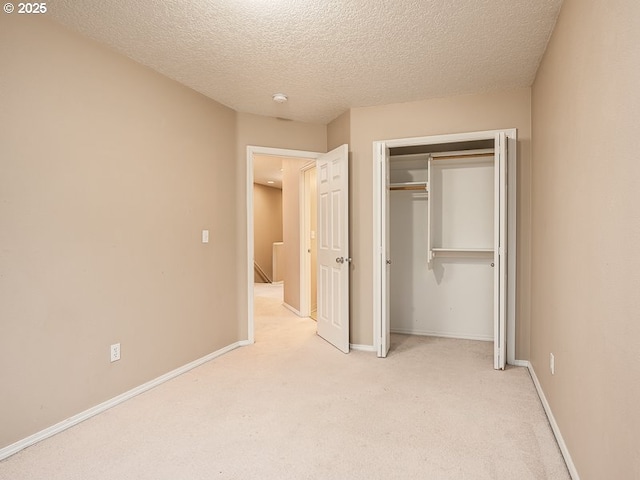 unfurnished bedroom with a closet, light carpet, and a textured ceiling