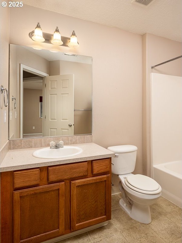 full bathroom with vanity, a textured ceiling, shower / washtub combination, and toilet