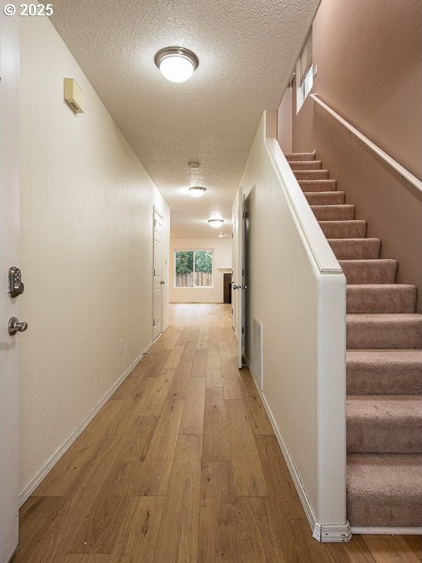 corridor featuring hardwood / wood-style flooring and a textured ceiling