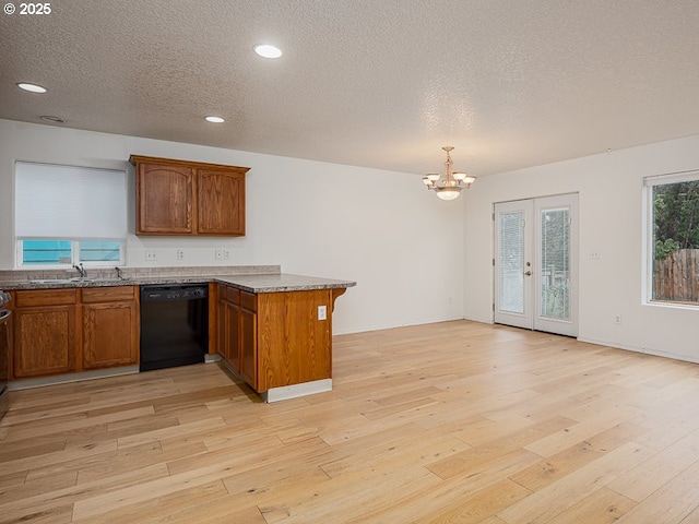 kitchen featuring sink, hanging light fixtures, light hardwood / wood-style flooring, black dishwasher, and kitchen peninsula