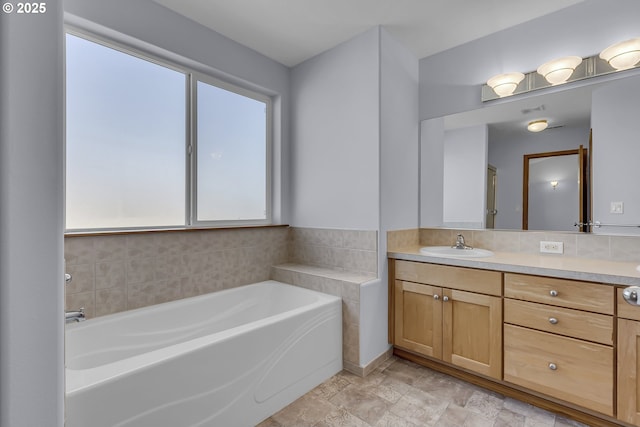 13007 SE Raymond Ct, Portland, OR 97236 - bathroom featuring vanity, a garden tub, decorative backsplash, and stone finish flooring