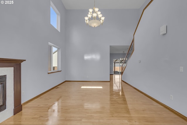 13007 SE Raymond Ct, Portland, OR 97236 - unfurnished living room featuring a chandelier, light wood-style floors, a towering ceiling, baseboards, and a fireplace